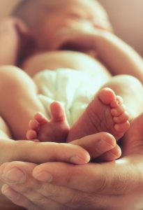 strong male hands holding sleeping newborn baby, photo with soft blur effect