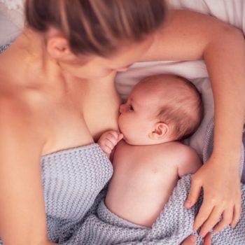 Happy young woman breastfeeding and hugging baby. Lactation newborn concept. Happy young woman breastfeeding and hugging baby. mom breastfeeding newborn child lying on bed. Lactation newborn concept. Baby eating milk before sleeping. Mother feed her month son with breast milk