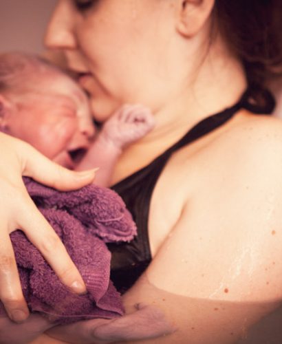 Mother Holding Newborn Baby in Birthing Pool After Home Birth