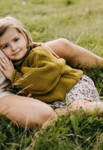 Little girl leaning on her pregnant mother belly, hugging, listening to what is inside the belly. Big sister concept.